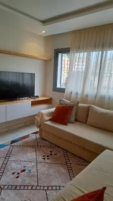 a living room with a couch and a flat screen tv at Bel appartement familial résidence sécurisée in Casablanca