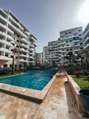 a swimming pool in front of some apartment buildings at Appartement Vue Mer & Coucher de Soleil in Aïn Harrouda