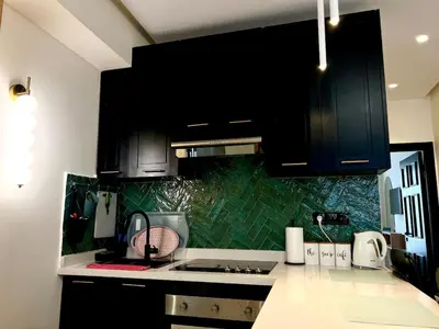 a kitchen with black cabinets and green tiles at Cozy apartment Casablanca in Casablanca