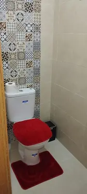 a bathroom with a toilet with a red seat at Logement cozy in Oulad Kerroum