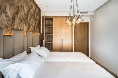 a bedroom with a large white bed and a chandelier at Contemporary apartment in CFC Anfa in Casablanca