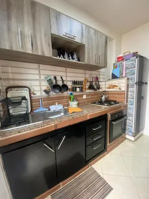 a kitchen with wooden cabinets and a stainless steel refrigerator at Appartement confortable et ensoleillée in Aïn Harrouda