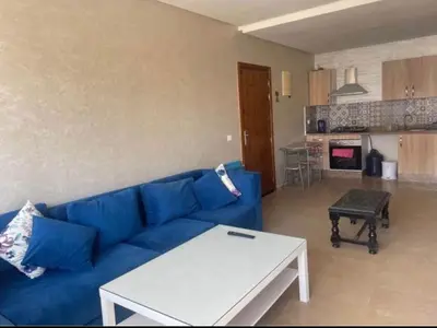 a living room with a blue couch and a kitchen at Appartement spacieux in Mohammedia