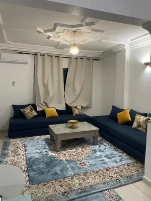 a living room with a blue couch and a table at Un petit studio in Settat