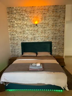 a bed with a green headboard and a brick wall at Appartement Agdal in Rabat