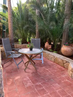 a patio with a table and two chairs and palm trees at Palmeraie 3 in Skhirat