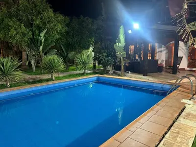 a large blue swimming pool at night with a light at Villa luxueuse à Skhirat Rabat in Skhirat