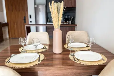 a wooden table with plates and wine glasses on it at Luxury business 70m apartment -CFC AERIA Mall Casa in Casablanca