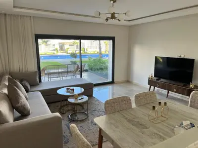 a living room with a couch and a tv and a table at Luxury 2 bedroom flat in Tamaris Dar Bouazza in Casablanca