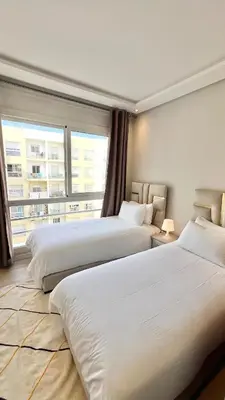 a hotel room with two beds and a large window at N42 Luxe et Élégance avec Jacuzzi Privatif sur la Corniche Rabat Essabah in Rabat