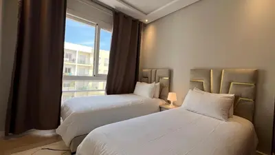 two beds in a hotel room with a window at N42 Luxe et Élégance avec Jacuzzi Privatif sur la Corniche Rabat Essabah in Rabat
