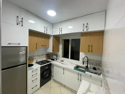 a kitchen with white cabinets and a sink and a dishwasher at Blue Beach & Sunny Life in Skhirate in Skhirat