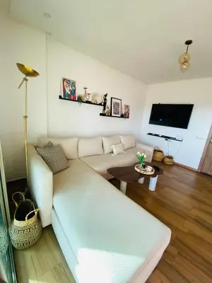 a living room with a white couch and a flat screen tv at Sidi rahal blue beach Cozy apartment with a sea view in Sidi Rahal