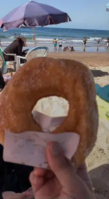 a person holding a donut in front of the beach at Appartement skhirat in Skhirat