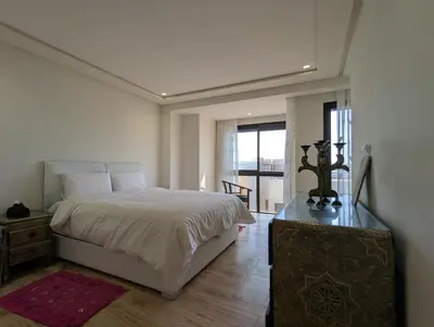 a white bedroom with a bed and a wooden floor at Seafront Luxury Villa with Amazing pool! in Dar Bouazza