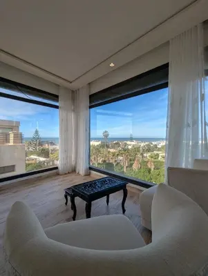 a living room with two chairs and a table and large windows at Seafront Luxury Villa with Amazing pool! in Dar Bouazza