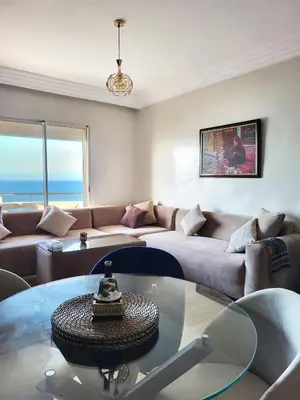 a living room with a couch and a glass table at Ailes du vent, coucher de soleil,vue sur mer in Rabat