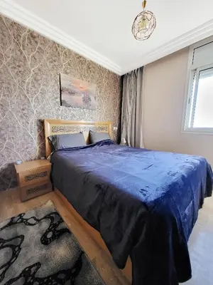 a bedroom with a large bed with a blue comforter at Ailes du vent, coucher de soleil,vue sur mer in Rabat