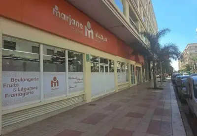 a building on the side of a street with parking meters at Neuf 3min de la plage au parc avec parking in Mohammedia