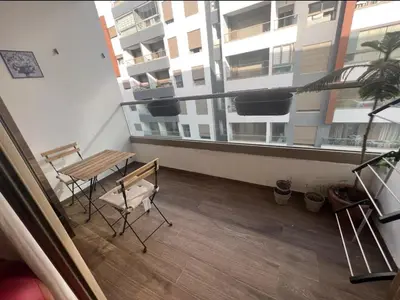 a balcony with a table and chairs in a building at Neuf 3min de la plage au parc avec parking in Mohammedia