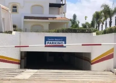 a parking garage in front of a building at Appartement balnéaire équipé in Sidi Rahal