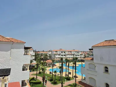 a view of a resort with a pool and buildings at Appartement balnéaire équipé in Sidi Rahal