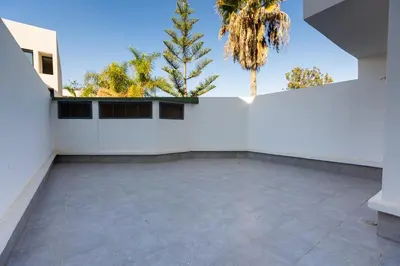 a large patio with a white wall and palm trees at Acacia Studios in Casablanca
