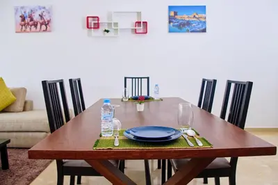 a wooden table with a plate and glasses on it at Luxueux studio spacieux à racine Casablanca à une minute de twin center in Casablanca