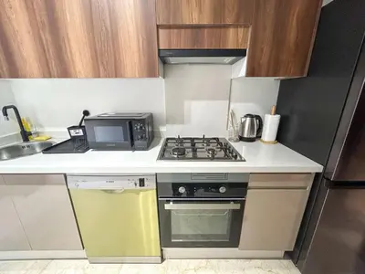 a small kitchen with a stove and a microwave at Appartement luxueux 2 Chambres avec salle de sport et parking in Casablanca