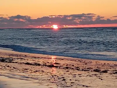 a sunset on the beach with the sun setting at apart Blanca beach sur mer in Sidi Rahal