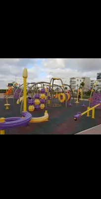 a playground with purple and yellow equipment in a parking lot at apart Blanca beach sur mer in Sidi Rahal