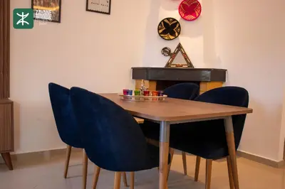 a dining room table with blue chairs and a clock at Beachside Retreat Rabat - Zayane Homes in Temara