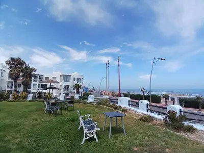 a patio with tables and chairs on the grass at Appartement Lumineux Front de Mer à CASABLANCA in Casablanca