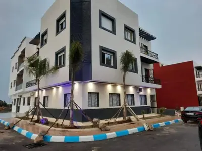 a building with palm trees in front of it at Dahomy bouzni9a in Bouznika