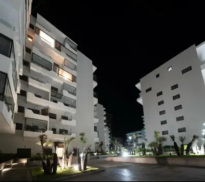 two tall buildings in a city at night at Luxury & sweet studio apartment with swimming pool in Aïn Harrouda