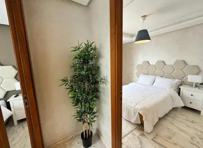 a bedroom with a bed and a potted plant at Résidence Saphir Luxury apartment with terrace in Racine in Casablanca