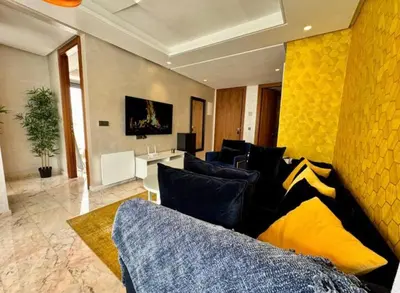 a living room with a couch and a yellow wall at Résidence Saphir Luxury apartment with terrace in Racine in Casablanca