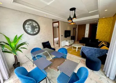 a living room with blue chairs and a clock on the wall at Résidence Saphir Luxury apartment with terrace in Racine in Casablanca