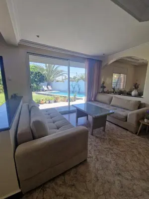 a living room with a couch and a table at Villa spacieuse avec piscine proche aéroport Mohamed V in Nouaseur