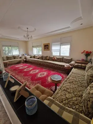 a large living room with a large red rug at Villa spacieuse avec piscine proche aéroport Mohamed V in Nouaseur