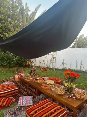 a picnic table under a black umbrella in the grass at Villa spacieuse avec piscine proche aéroport Mohamed V in Nouaseur