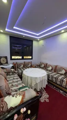 a living room with a table and couches and a room with a blue ceiling at Spacious apartment in Settat