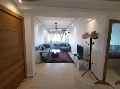 a living room with a couch and a television at Sunny apartment in El Harhoura