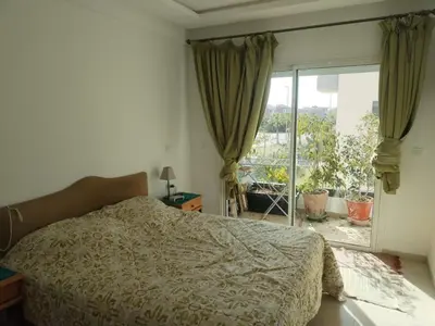 a bedroom with a bed and a large window at Sunny apartment in El Harhoura