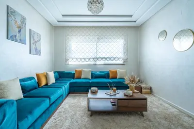 a living room with a blue couch and a table at Charming Flat with Pool view Fast Wi-Fi in Bouznika