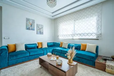 a living room with a blue couch and a coffee table at Charming Flat with Pool view Fast Wi-Fi in Bouznika