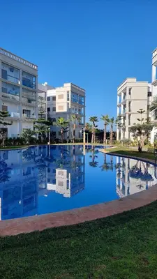 a large swimming pool in front of some buildings at Charming Flat with Pool view Fast Wi-Fi in Bouznika