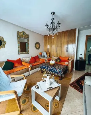a living room with orange furniture and a chandelier at Élégance et Sérénité au Cœur de Casablanca in Casablanca
