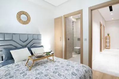 a bedroom with a bed with a table and a bathroom at Nice & Comfortable 2BHK panoramic balcony with swimming pool in Aïn Harrouda
