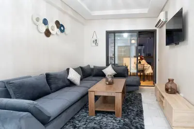 a living room with a blue couch and a table at Nice & Comfortable 2BHK panoramic balcony with swimming pool in Aïn Harrouda